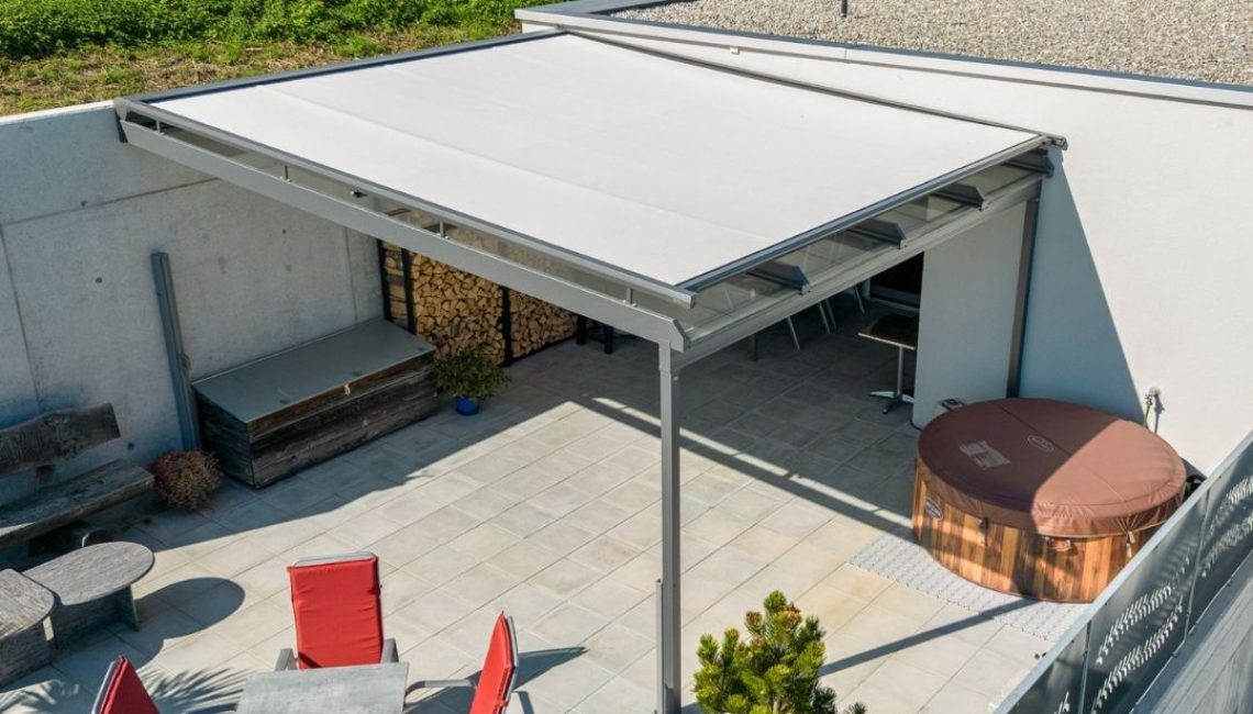 Terrasse mit Glasdach und integrierter Beschattung – Sitzgruppe mit roten Stühlen, Whirlpool und Pflanzen im modernen Outdoor-Bereich.