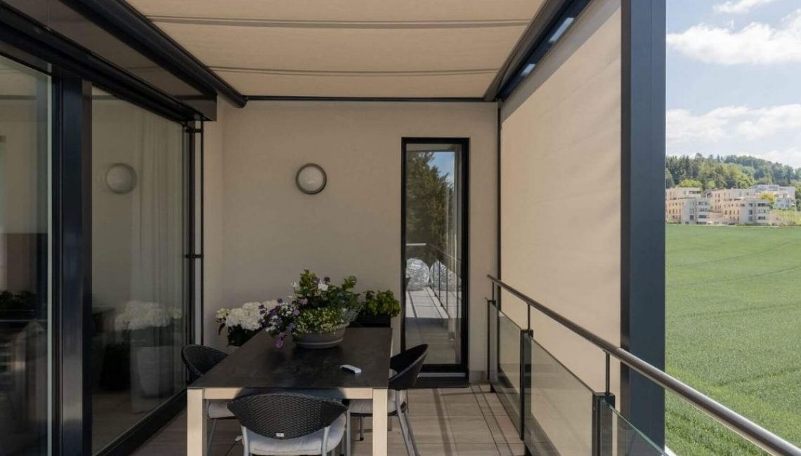 Überdachte Terrasse mit Glasdach und integriertem Sonnenschutz in Uitikon Waldegg, modern eingerichtet mit Esstisch und Stühlen.