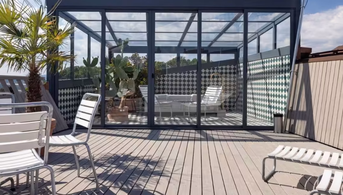 Glasdach Orangerie auf Dachterrasse in Kloten mit Glaswänden und eleganter Konstruktion, schützt Pflanzen im Winter und dient im Sommer als Treffpunkt.