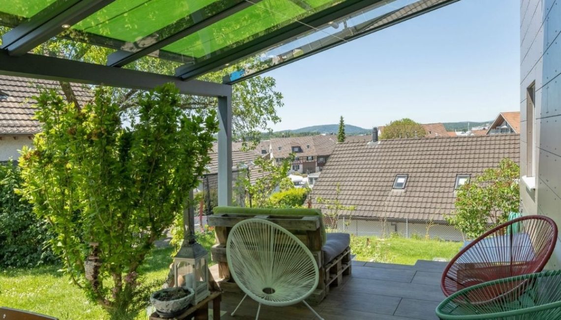 Gemütlicher Sitzbereich unter dem SGL 1 Glasdach in Bachenbülach mit Blick über die Dächer der Umgebung