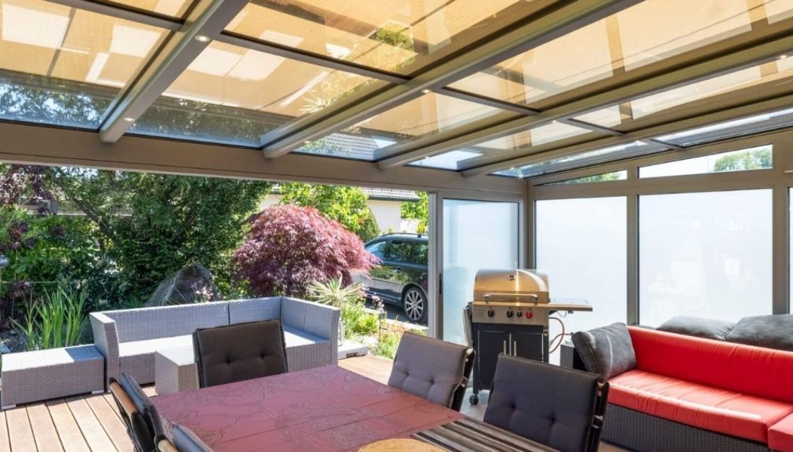 Innenaufnahme eines Glasdachs in Neerach Zürich mit Beschattung, gemütlicher Sitzgruppe und Esstisch, ideal für den geschützten Aussenbereich.