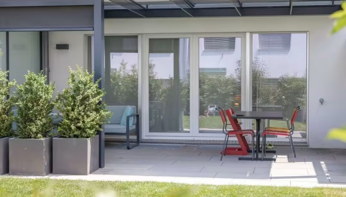 Modernes Glasdach in Ostermundigen, das den Sitzplatz vor dem Haus überdeckt und zuverlässigen Schutz mit einer Schneelast von bis zu 380 kg/m² bietet.
