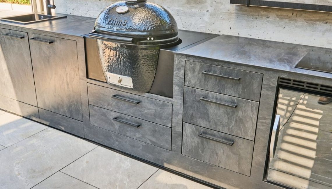 Detailansicht einer Theiss Outdoor-Küche mit Keramikgrill, Spülbecken, Stauraum und Kühlschrank in modernem Design.