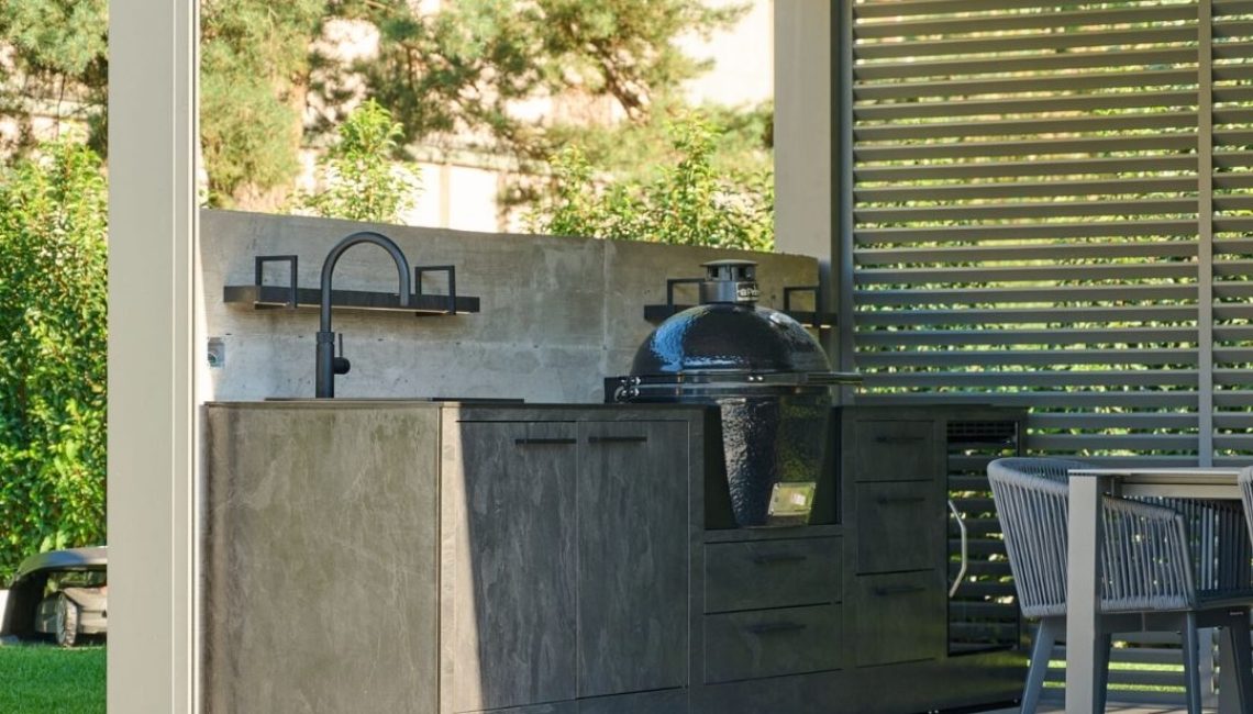Outdoor-Küche mit Grill und Spüle unter einem modernen Lamellendach, direkt am Poolbereich in Münchenstein (BL).