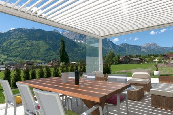 Weisses SKL 100 Lamellendach mit Glaswänden und Blick auf die Schweizer Alpen.