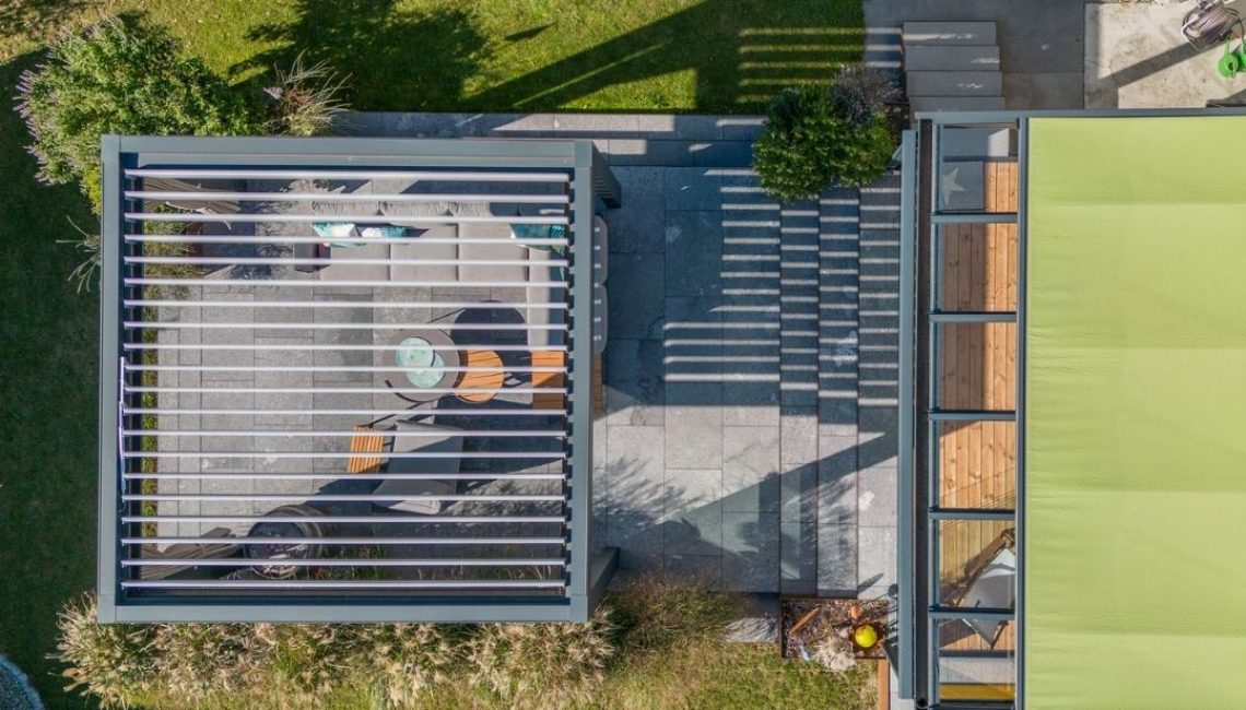 Draufsicht auf eine moderne Kombination aus Lamellendach und Wintergarten im Gartenbereich.
