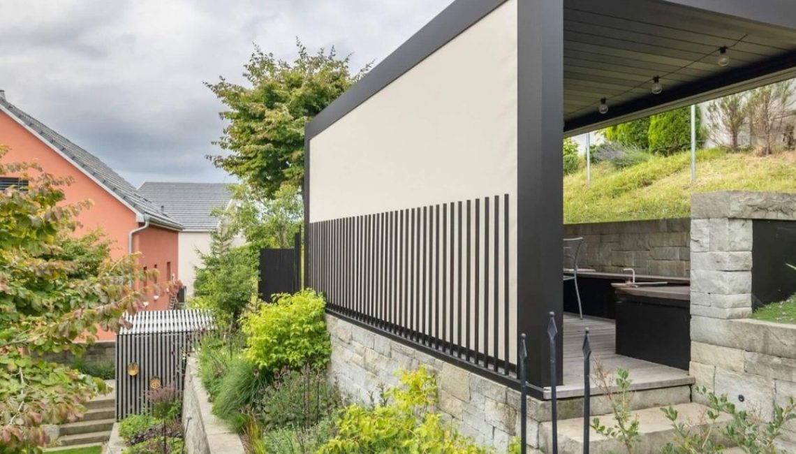 Lamellendach in Teufen Appenzell mit seitlichem Sicht- und Sonnenschutz, eingebettet in eine erhöhte Gartenterrasse.