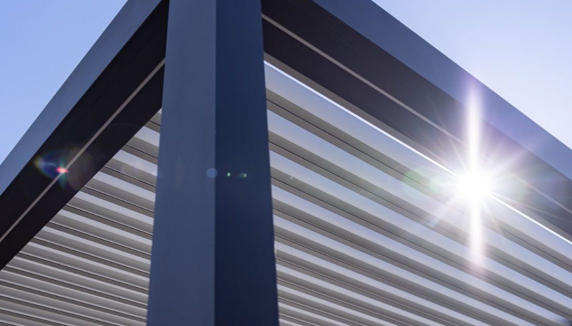 Nahaufnahme eines modernen Lamellendachs aus Aluminium, fotografiert von unten gegen die Sonne.