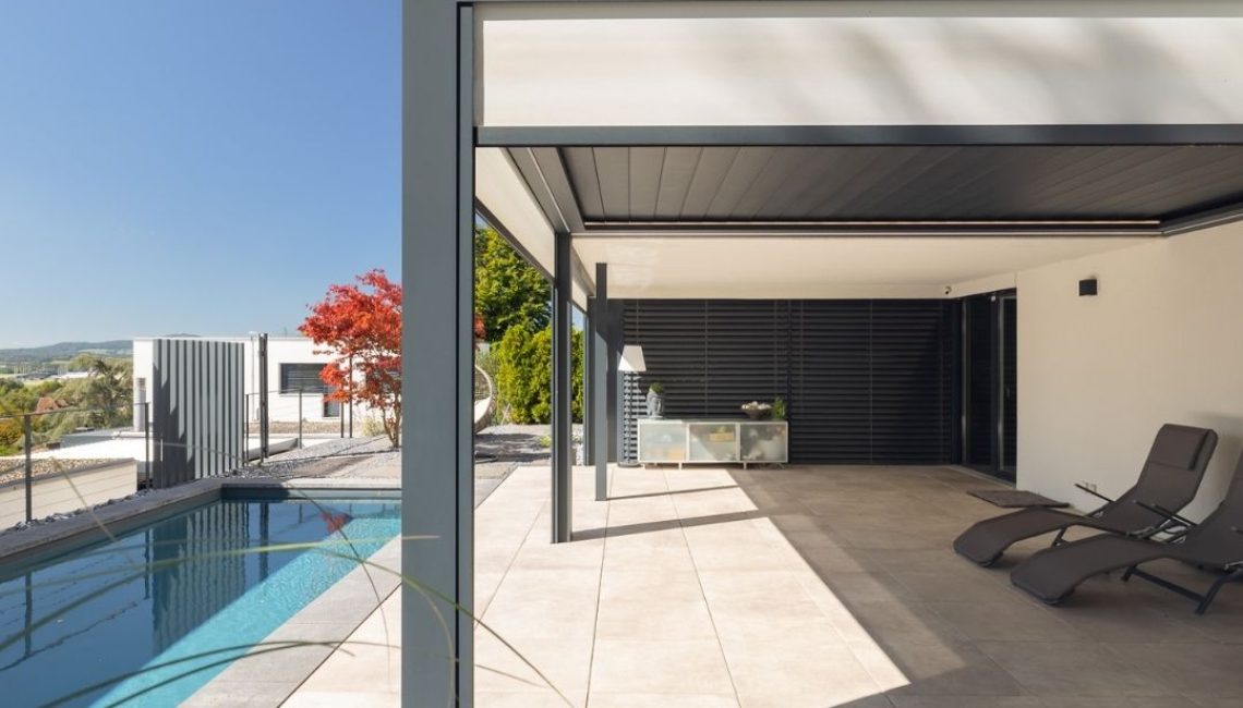 SKL 140 Lamellendach über Poolterrasse – grosszügiger überdachter Bereich mit Liegestühlen und modernem Hausanschluss.