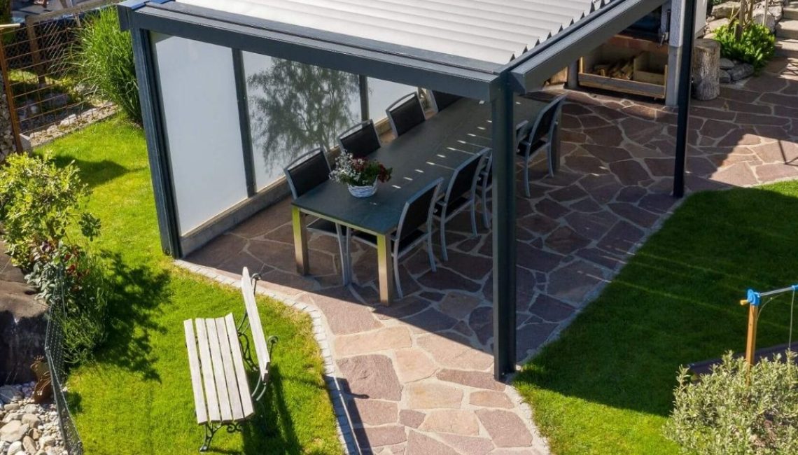 Lamellendach in Eggersriet St. Gallen mit seitlichen Sichtschutz-Elementen und grossem Essbereich im Garten.