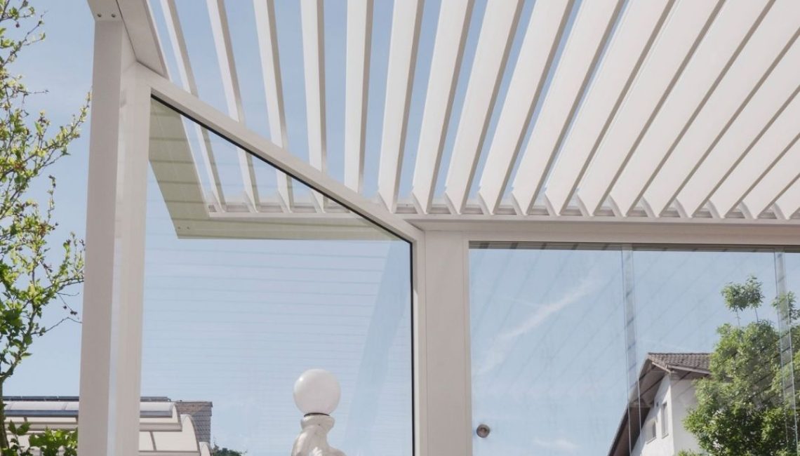 Nahaufnahme eines weissen SKL 100 Lamellendachs in Root, Luzern, mit Glaswänden und Statue im Vordergrund.