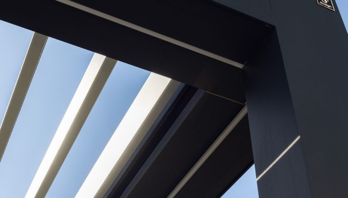 Nahaufnahme eines modernen Lamellendachs aus Aluminium, mit geöffneten Lamellen und klarem Himmel im Hintergrund.