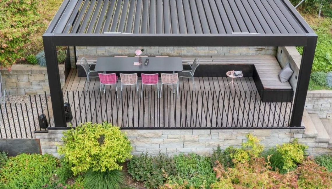 Modernes Lamellendach in Teufen Appenzell mit grossem Esstisch und Lounge-Bereich auf einer erhöhten Holzterrasse.