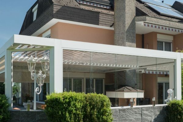 SKL 100 Lamellendach mit Glaswänden an einem Einfamilienhaus, ausgestattet mit integriertem Grillbereich.