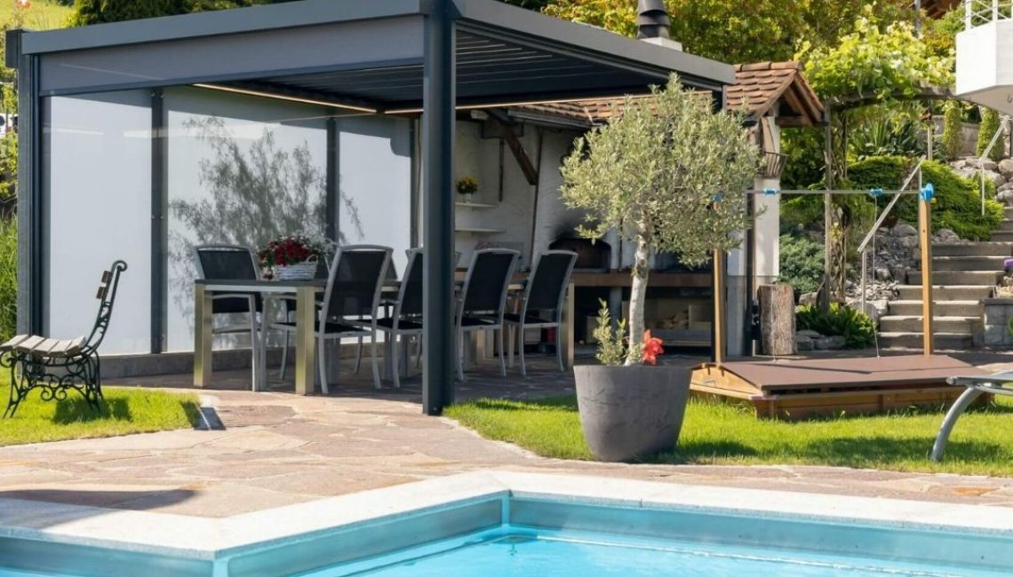 Lamellendach mit Glaswänden in Eggersriet St. Gallen, moderne Outdoor-Oase mit Essbereich und Pool.