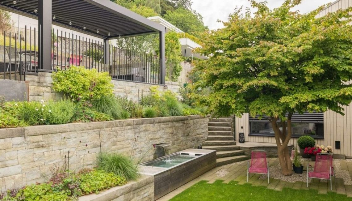 Lamellendach in Teufen Appenzell, integriert in einen terrassenförmig angelegten Garten mit Natursteinmauern, Wasserbecken und Sitzbereich.