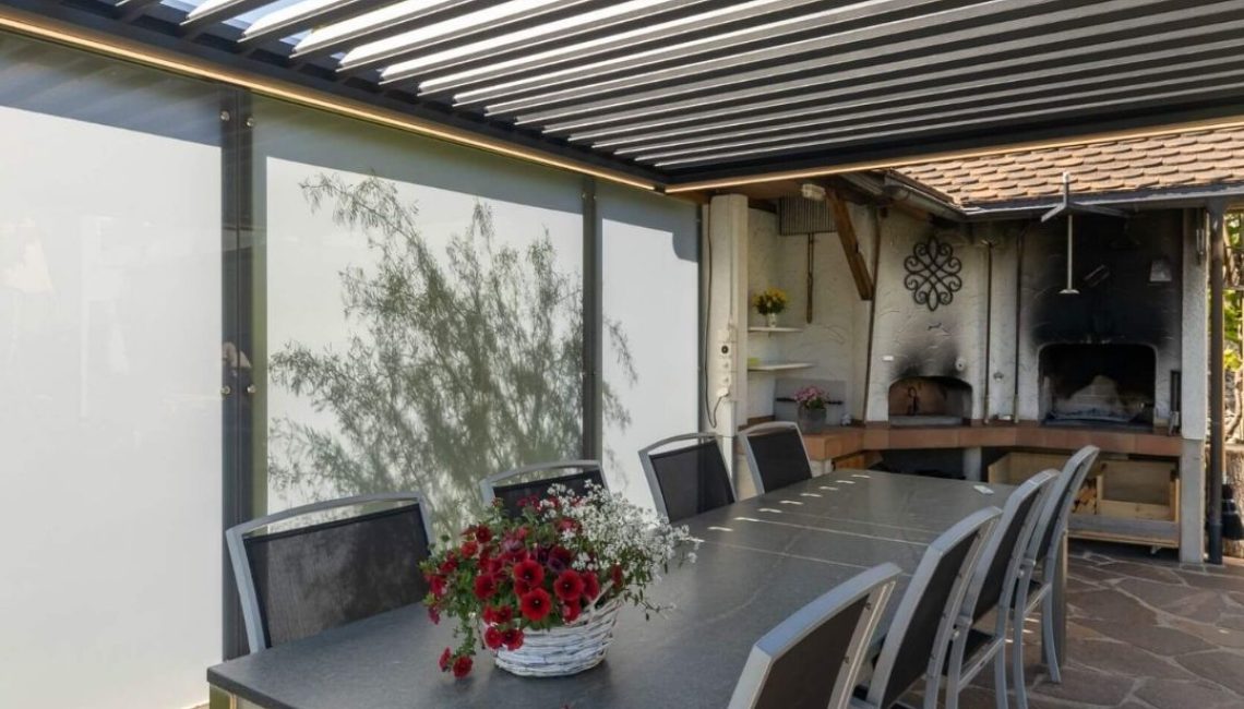 Lamellendach in Eggersriet St. Gallen mit geöffneten Lamellen, seitlichen Screens und angrenzender Outdoor-Küche.