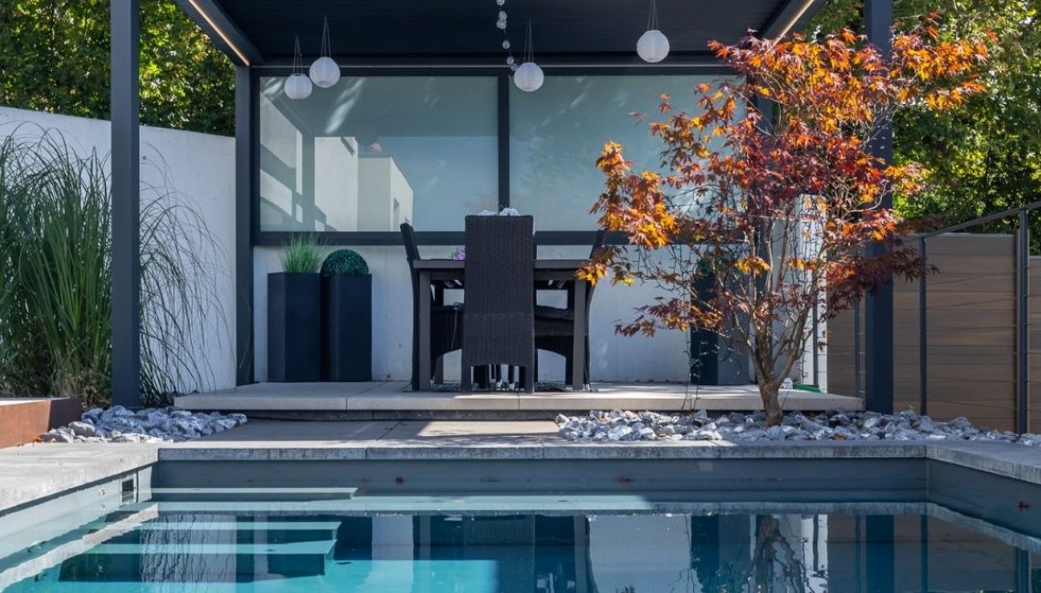 SKL 100 Lamellendach über Terrasse am Pool – moderne Überdachung mit hoher Schneelast von bis zu 300 kg/m², Sitzgruppe und stilvollem Gartenambiente.