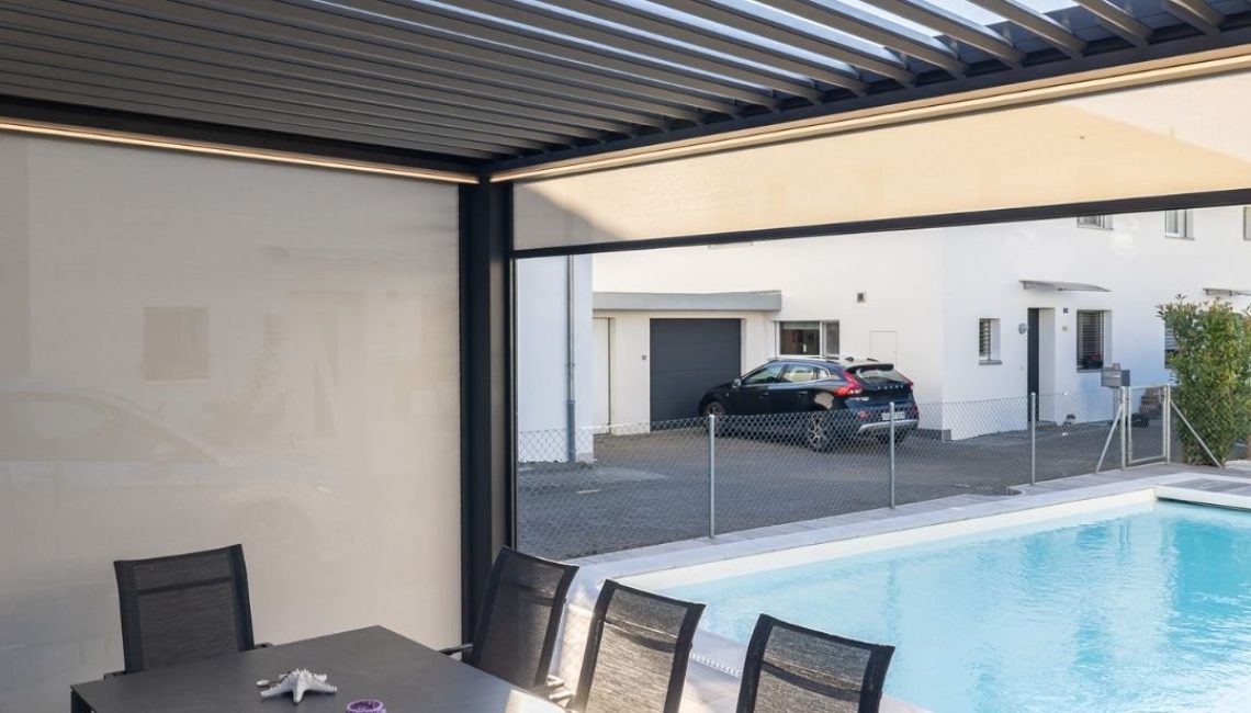 Lamellendach mit integriertem Sonnenschutz über einer Sitzgruppe am Pool, moderne Outdoor-Oase im Garten in Ehrendingen Aargau.