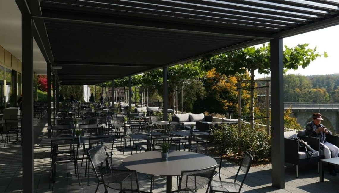 SKL 100 Lamellendach in Hinterkappelen Bern über einer weitläufigen Restaurantterrasse mit modernen Sitzplätzen und Blick auf die Aare.