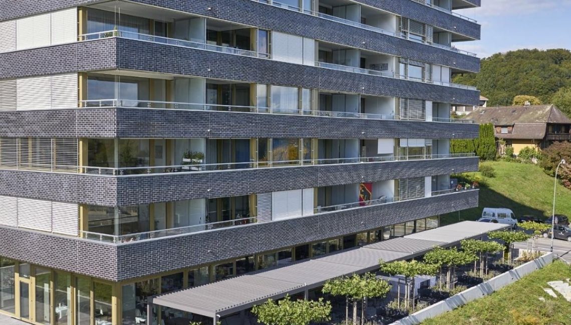 Modernes Wohngebäude in Hinterkappelen Bern mit grossflächigem SKL 100 Lamellendach über der Terrasse und integriertem Sitzbereich.