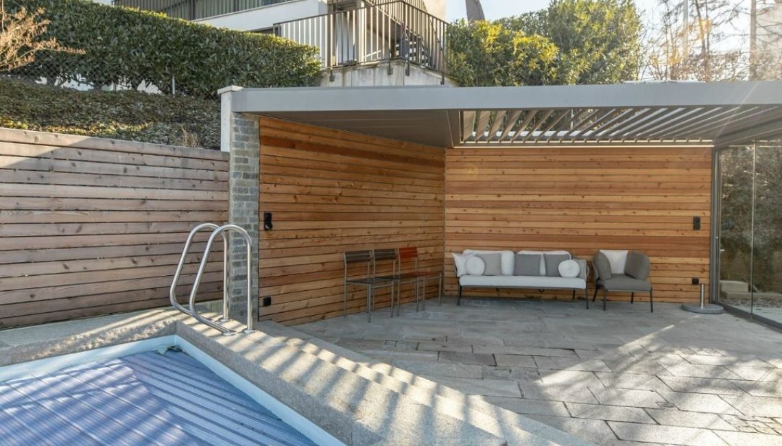 SKL 100 Lamellendach in Horgen Zürich mit 300 kg/m² Schneelast – moderne Outdoor-Lounge mit Holzverkleidung und Pool im Vordergrund.