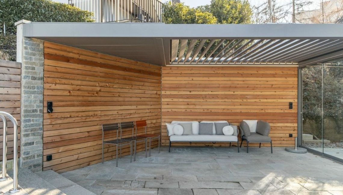 SKL 100 Lamellendach in Horgen, Zürich – überdachte Lounge mit Natursteinboden und Holzverkleidung, wetterfest und stabil bei üblicher Schneelast.