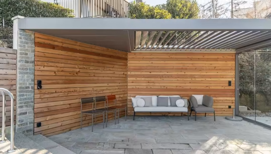 SKL 100 Lamellendach in Horgen, Zürich – überdachte Lounge mit Natursteinboden und Holzverkleidung, wetterfest und stabil bei üblicher Schneelast.