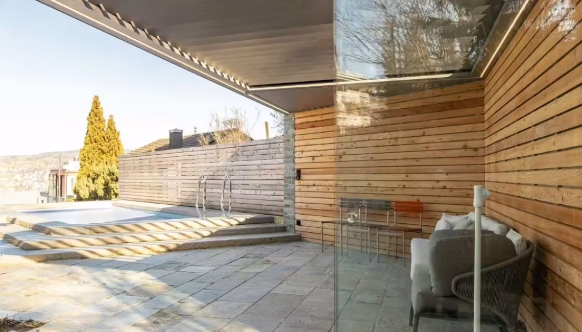 SKL 100 Lamellendach in Horgen, Zürich – moderne Überdachung mit Glasfronten und Blick auf den Pool, stabil bei üblichen Schneelasten.