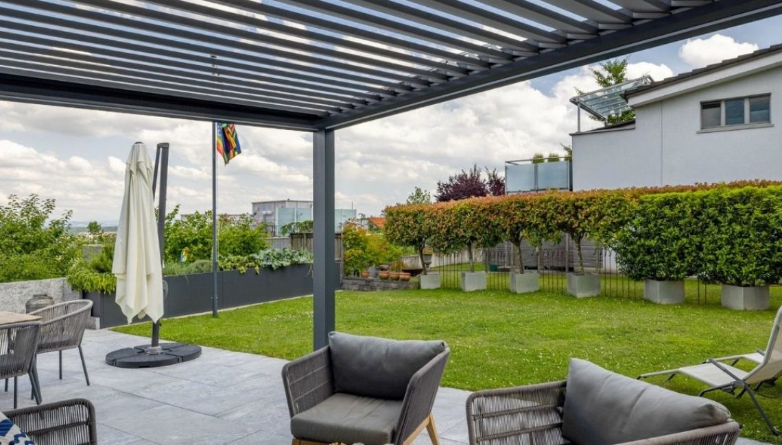 Moderne Gartengestaltung mit SKL 100 Lamellendach in Rümlang Zürich – gemütliche Lounge unter stabiler Überdachung.