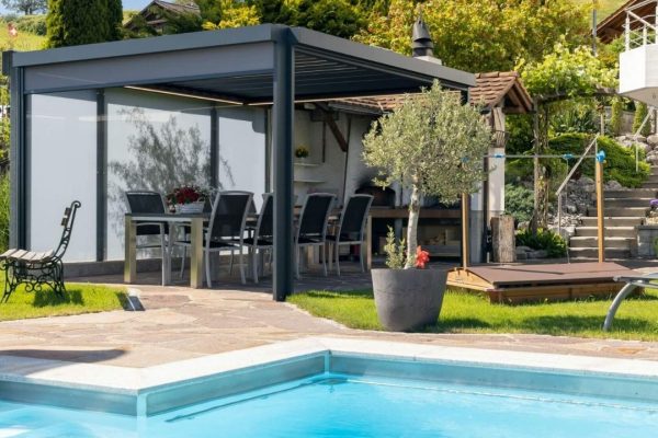 SKL 50 Lamellendach mit geschlossenen Seitenmarkisen neben einem Pool in moderner Gartenanlage.