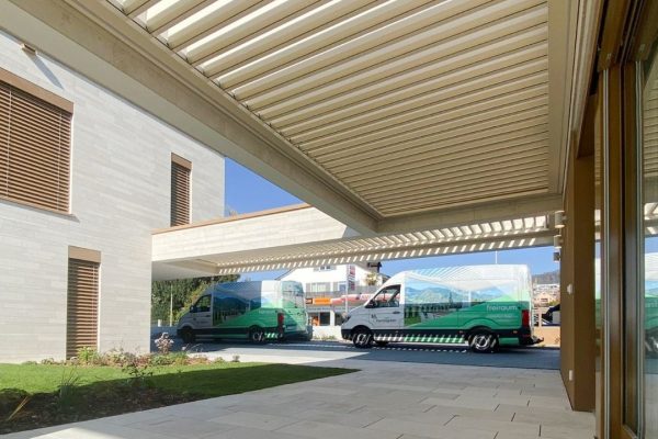 SKL 50 SKY Lamellendach an einem modernen Gebäude mit Thermogreen-Fahrzeugen im Hintergrund.