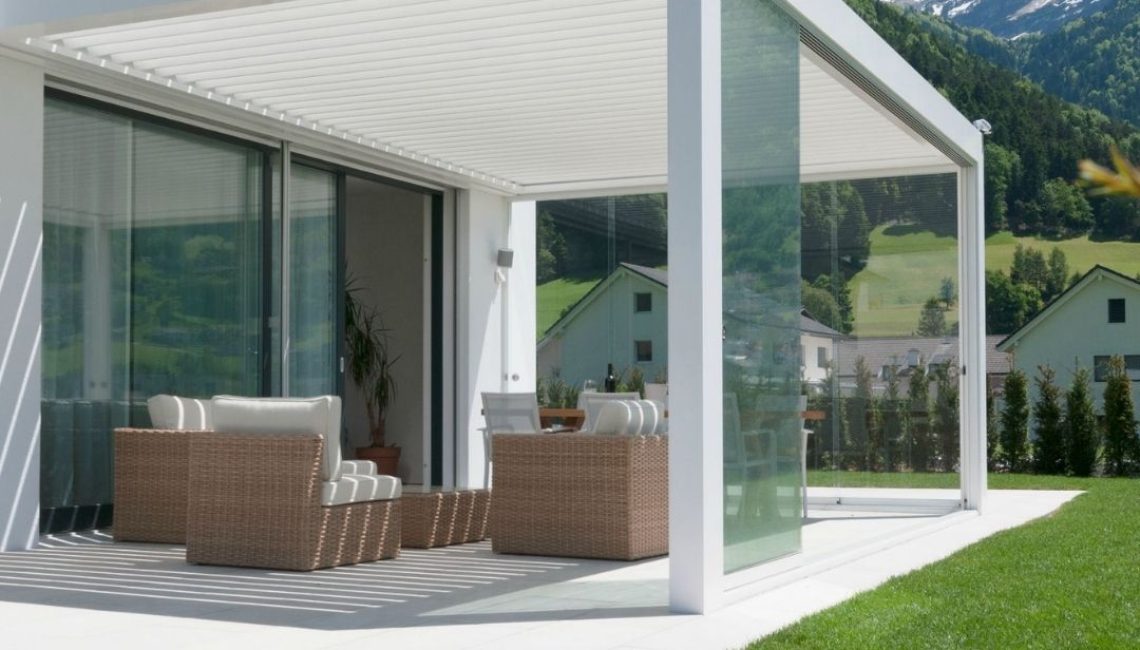 Weisses SKL 100 Lamellendach in Schattdorf, Uri – mit Glaswänden und 300 kg/m² Schneelast, harmonisch integriert in eine moderne Architektur mit Bergkulisse.