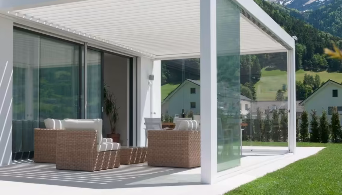 Weisses SKL 100 Lamellendach in Schattdorf, Uri – mit Glaswänden und 300 kg/m² Schneelast, harmonisch integriert in eine moderne Architektur mit Bergkulisse.