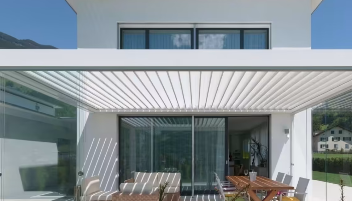 SKL 100 Lamellendach in Schattdorf, Uri – weisses Aluminiumdach mit Glaswänden und 300 kg/m² Schneelast, integriert in ein modernes Einfamilienhaus.