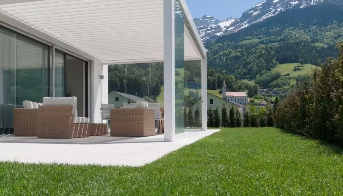 SKL 100 Lamellendach in Schattdorf, Uri – weisse Aluminiumkonstruktion mit Glaswänden und Blick auf die verschneiten Alpen, Schneelast 300 kg/m².