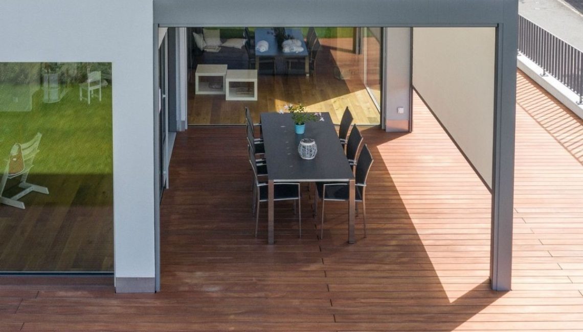 SKL 140 Lamellendach in Schwarzenberg, Luzern – moderne Überdachung mit geschlossenen Lamellen über einer stilvollen Holzterrasse und grossem Esstisch.