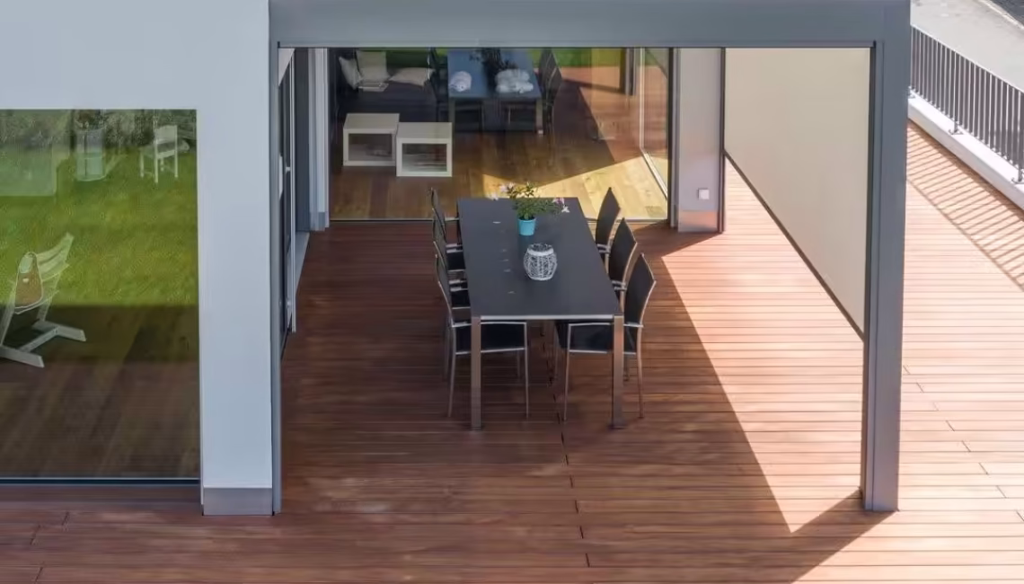 SKL 140 Lamellendach in Schwarzenberg, Luzern – moderne Überdachung mit geschlossenen Lamellen über einer stilvollen Holzterrasse und grossem Esstisch.