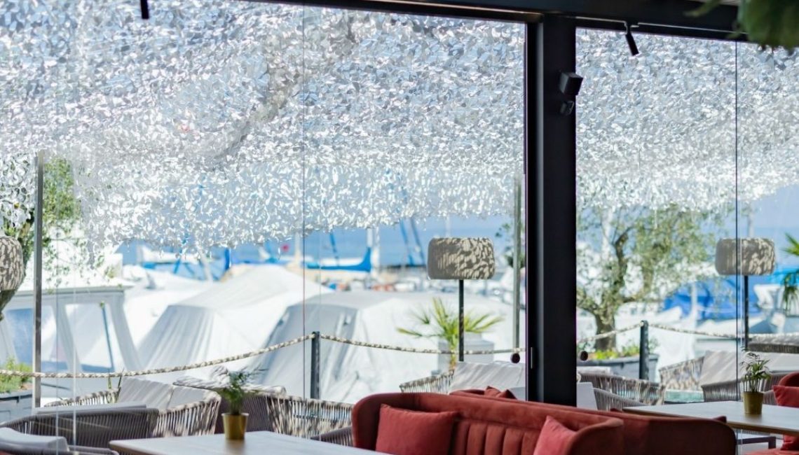 SKL 100 Lamellendach im Restaurant Al Porto in Thal St. Gallen mit Glasfront und Blick auf den Hafen.