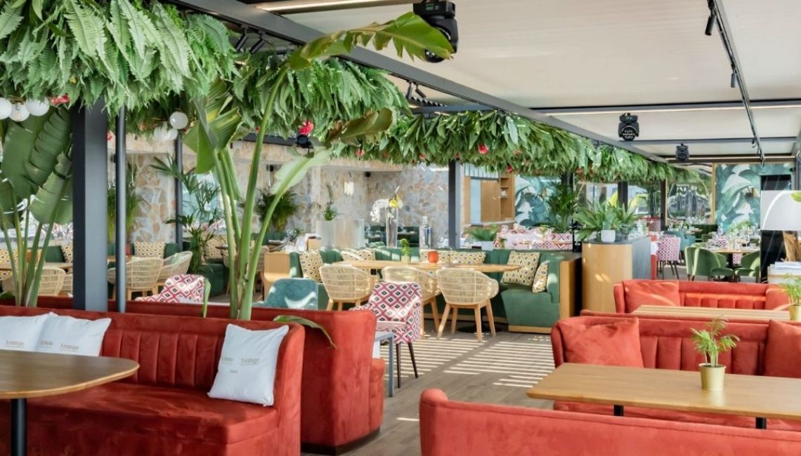 SKL 100 Lamellendach mit offener Struktur im Restaurant Al Porto in Thal St. Gallen, kombiniert mit farbenfrohem Interieur und üppiger Begrünung.