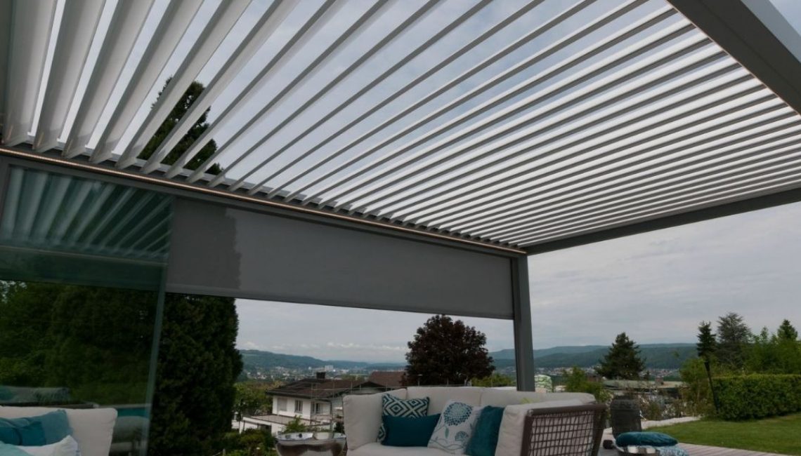 Geöffnetes SKL 100 Lamellendach in Urdorf Zürich mit modernem Lounge-Bereich und Blick über die Umgebung.