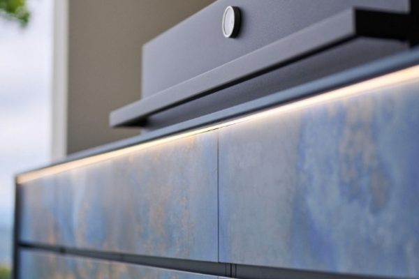 Nahaufnahme einer exklusiven Outdoor Küche mit blauen Fronten und integrierter LED-Beleuchtung.