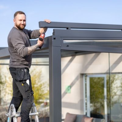 Thermogreen Monteur arbeitet an einer Terrassenüberdachung während Montage oder Wartung