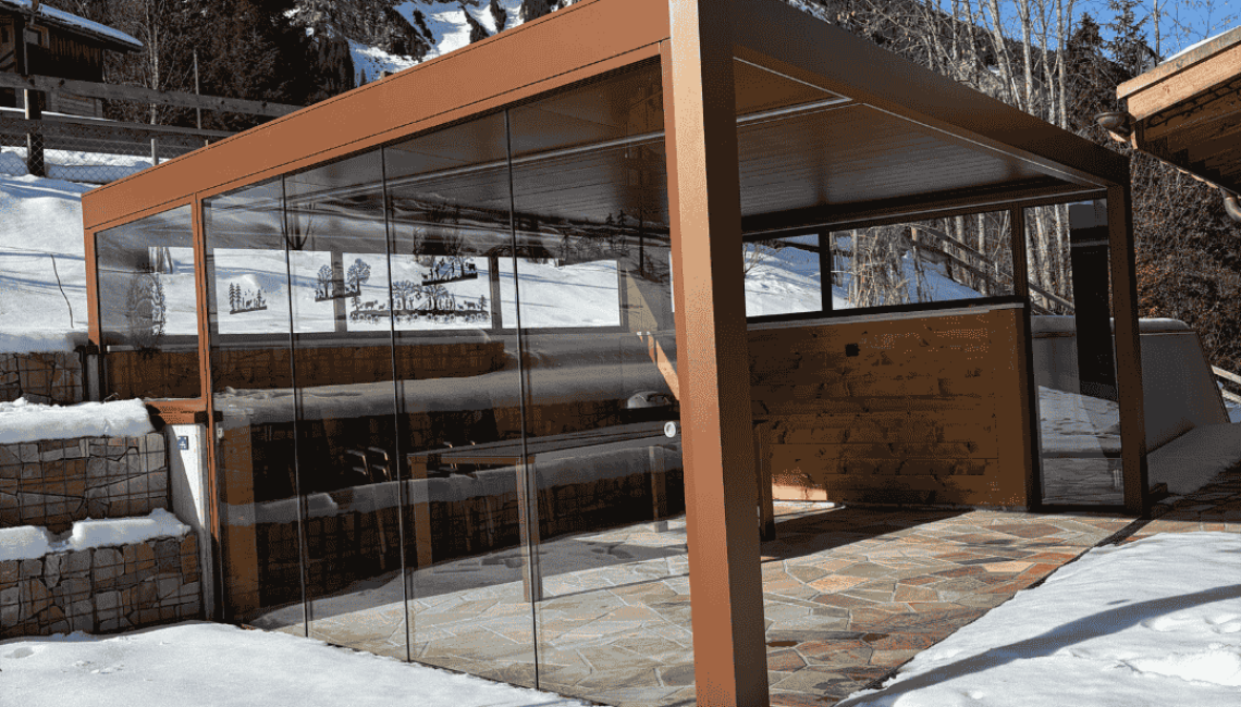 Lamellendach in Sonderform mit Ganz-Glas-Schiebeanlage auf einer Terrasse in Lenk im Simmental, umgeben von Schnee und alpiner Berglandschaft.