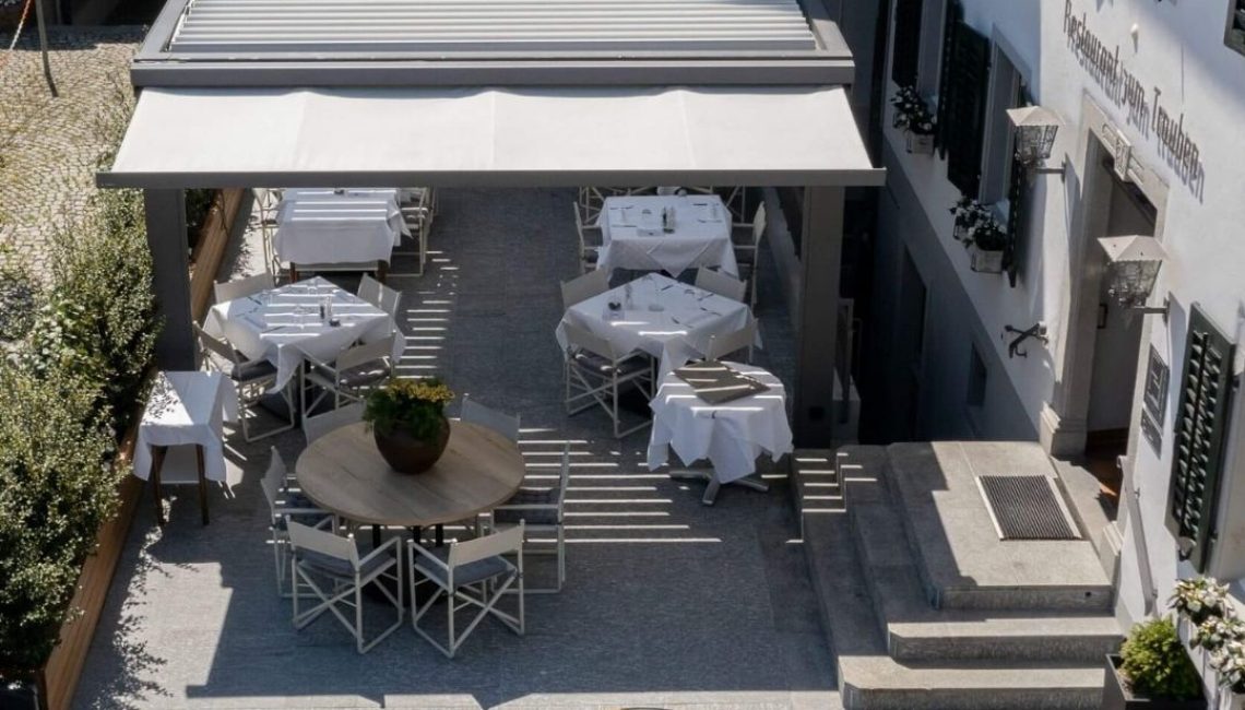 Lamellendach auf der Terrasse eines Restaurants in Küsnacht, das den Gästen wettergeschützte Sitzplätze bietet.