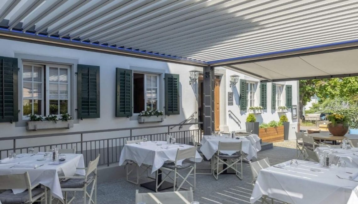 Restaurantterrasse in Küsnacht mit Lamellendach, gedeckten Tischen und gemütlicher Atmosphäre.