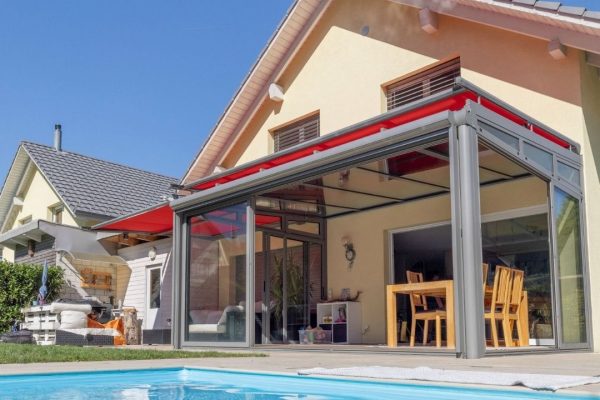 SGL 1 Glasdach mit Schiebeverglasung und integrierter Markise in Rot, geprüft bis 350 kg/m² Schneelast, moderne Wohnraumerweiterung am Pool.