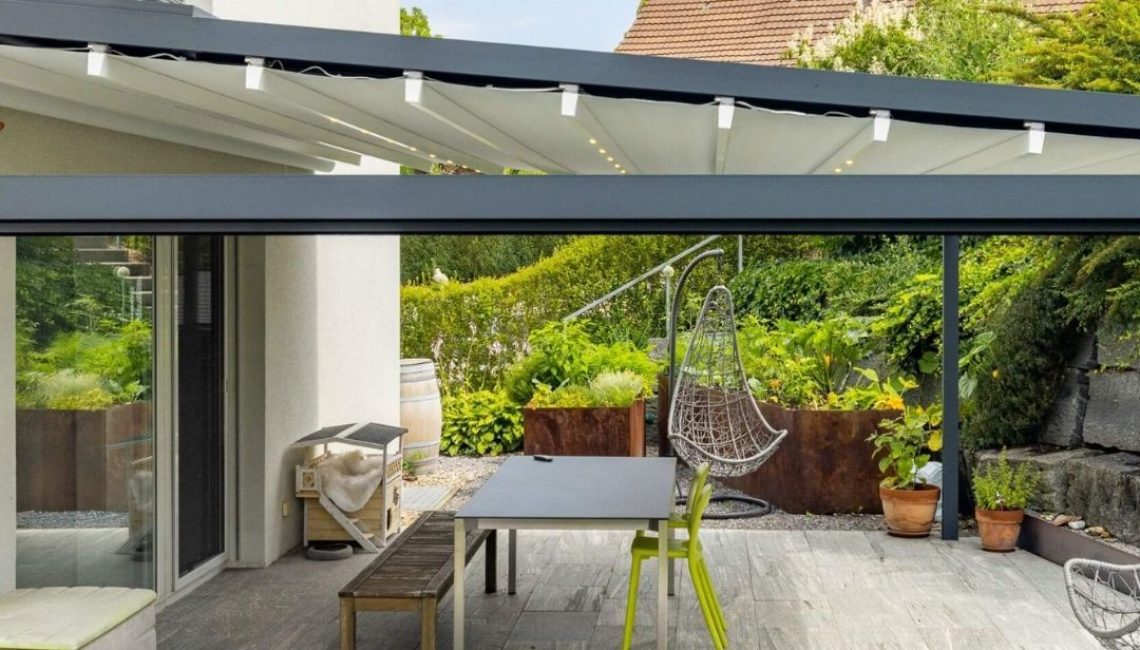 Moderner Sitzplatz mit Textildach in Henggart Zürich, ausgestattet mit Esstisch, Hängesessel und LED-Beleuchtung.